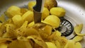Potato peelings fall on raw potatoes in the sink. Knife stuck in raw potatoes