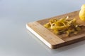 Potato peelings with potatoes on wooden cutting board on grey background
