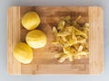 Potato peelings with potatoes on wooden cutting board on grey background. Top view