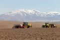 Two farmers in tractors planting potatoes.