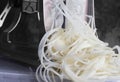 Potato on a spiralizer being cut into thin strips.