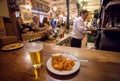 Potato tapas on plate and glass of beer for customer of busy fast-food restaurant in traditional spanish style