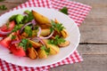 Potato wedges, cooked broccoli, fresh tomato slices with spices, red onion, green parsley leaves on a white plate Royalty Free Stock Photo