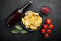 Potatoe chips, with bottle of beer , on black stone background, top view flat lay Royalty Free Stock Photo