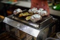 Potatoes in aluminum foil grilling on bbq, summer food