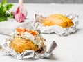 Potatoes baked in foil with cream cheese filling lie on the table
