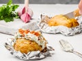 Potatoes baked in foil with cream cheese filling lie on the table