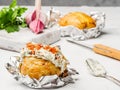Potatoes baked in foil with cream cheese filling lie on the table