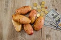 Potatoes, dollars, coins on a wooden table. View from above.