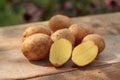 potatoes - a few raw organic potatoes in their skins and one potato cut in half, laid out on a wooden table Royalty Free Stock Photo