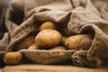 Potatoes in a jute sack on a wooden round chopping board