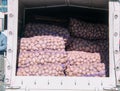 Potatoes in mesh bags in a trailer of a machine for sale at a farmers\' market.