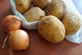 Potatoes and onions on wooden table