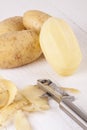 Potatoes with Peeler and Peeled Skin Royalty Free Stock Photo