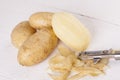 Potatoes with Peeler and Peeled Skin Royalty Free Stock Photo