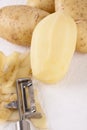 Potatoes with Peeler and Peeled Skin Royalty Free Stock Photo