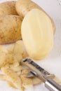 Potatoes with Peeler and Peeled Skin Royalty Free Stock Photo