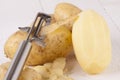 Potatoes with Peeler and Peeled Skin Royalty Free Stock Photo