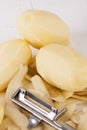 Potatoes with Peeler and Peeled Skin Royalty Free Stock Photo