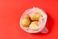 Potatoes in plastic bag on red background. Stop using artificial food storage bags concept