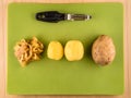 Potatoes, skins and peeler on green plastic board Royalty Free Stock Photo