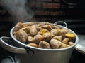 Potatoes with their skins in a stainless steel pot. ripe yam, visible smoke.