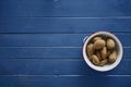 Potatoes in a white sieve on blue table Royalty Free Stock Photo