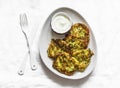 Potatoes, zucchini, herbs fritters with sour cream sauce on a light background, top view. Delicious breakfast, appetizer, tapas
