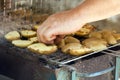 Potatos grilled on barbecue grill and cook`s hand