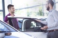 Potential buyer talking to a car dealer next to a car
