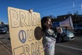 Potester with megaphone and large homemade sign saying Bring our Troops Home on street corner