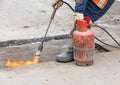 Patching a road by heating a damaged asphalt surface with a gas burner Royalty Free Stock Photo