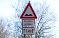 Pothole sign warning car driver at road damages german text translation `road damaged` Royalty Free Stock Photo