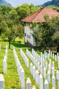 Potocari, Bosnia and Herzegovina - July 31, 2019. Tombstones with house demaged during war in background