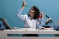 Potrait of crazy silly chemist analyzing glass test jars filled with liquid experiment serums while sitting at desk.