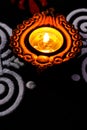 Potrait view of shining terracotta lamp with rangolis on black background. deepawali concept