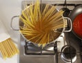 Pots with spaghetti, tomato sauce on a cooker and a spaghetti pack and view from above