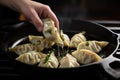 a potstickers being flipped by a hand in a cast iron pan Royalty Free Stock Photo