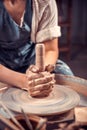 Young and cheerful woman is working on pottery wheel. Artisan production. Close-up.