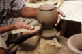 Potter hands making in clay on pottery wheel.