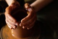 A potter hands moulding a clay pot on rotating potter`s wheel