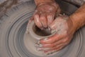 Potter with his hands beginning the transformation of piece of white clay into the pot on the wheel circle in studio. Concept of Royalty Free Stock Photo