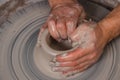 Potter with his hands beginning the transformation of piece of white clay into the pot on the wheel circle in studio. Concept of