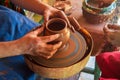 Potter makes on pottery wheel clay pot and conducts master class. Hands of master and child close up during work. Ancient national