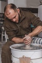 Potter making a jar pot of white clay on the potter`s wheel circle in studio, concept of creativity and art, vertical photo Royalty Free Stock Photo