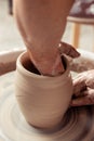 Potter making a jar pot of white clay on the potter`s wheel circle in studio, concept of creativity and creativity, vertical phot