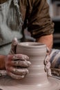 Potter making a jar pot of white clay on the potter`s wheel circle in studio, concept of creativity and art, vertical photo Royalty Free Stock Photo