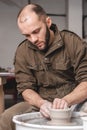 Potter making a jar pot of white clay on the potter`s wheel circle in studio, concept of creativity and art, vertical photo Royalty Free Stock Photo