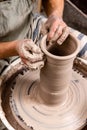 Potter making a jar pot of white clay on the potter`s wheel circle in studio, concept of creativity and art, vertical photo