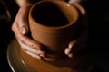 The potter`s hand in the product formed on a potter`s wheel. Red clay turns into a cup